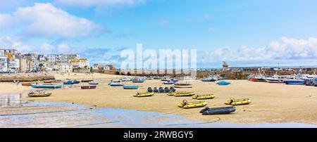 Urlauber, Tagesausflügler mit Fischerbooten und Motorbooten am Sandstrand von St. Ives, Cornwall. Stockfoto