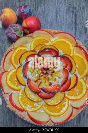 Ein Stück Pfirsichtorte mit frischen Früchten auf einem Holztisch, Blick von oben Stockfoto