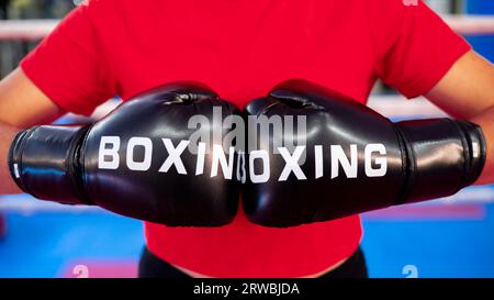 Zwei rote Boxhandschuhe zum Stanzen. Die Frau hat geprellt. Kickboxsport-Wettkampf. Stockfoto