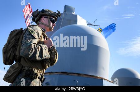 18. September 2023, Lettland, Ventspils (windau): Ein Soldat der amerikanischen Marine steht auf dem US-Marineschiff USS Mesa Verde während des großen Marinemanövers „Northern Coasts 23“ in der Ostsee vor der Küste Lettlands. Das von Deutschland geführte Marinemanöver, das bis zum 23. September 2023 läuft, zielt darauf ab, taktische Verfahren zur nationalen und allianzpolitischen Verteidigung in küstennahen Gewässern durchzuführen. Die Übung, die auch die Zusammenarbeit zwischen den Ländern der Ostseeregion stärken soll, umfasst 3.200 Soldaten und Frauen aus 14 Ländern. Foto: Bernd von Jutrczenka/dpa Stockfoto