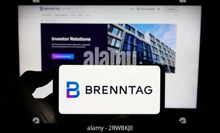 Person, die ein Mobiltelefon mit dem Logo des deutschen Chemikalienvertriebs Brenntag SE auf dem Bildschirm vor der Webseite hält. Konzentrieren Sie sich auf das Display des Telefons. Stockfoto