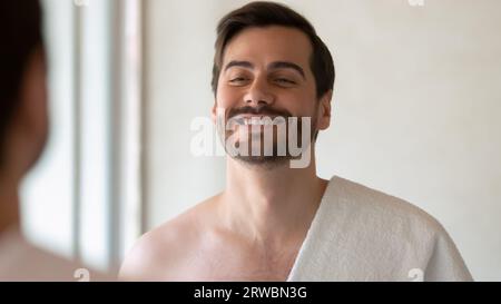 Kopfschuss gutaussehender Mann mit gesundem Lächeln im Spiegel Stockfoto