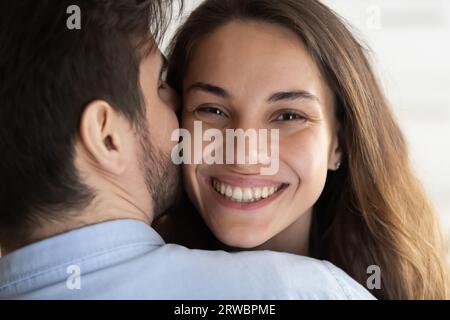 Nahaufnahme liebender Mann, der lächelnde, schöne Wange der Frau küsst Stockfoto
