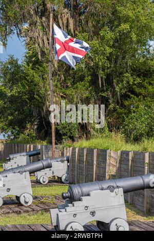 Zerrissene britische Flagge, die über Kanonen wehte, im wiederaufgebauten Fort King George aus dem 18. Jahrhundert am Altamaha River in Darien, Georgia. (USA) Stockfoto