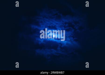 Fantastische Landschaft mit blau leuchtendem Mond in dunkelblauem Himmel mit Wolken in der Nacht Stockfoto