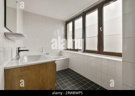 Geräumiges Badezimmer mit Badewanne und Keramikwaschbecken in einem modernen Apartment mit großen hellen Fenstern Stockfoto