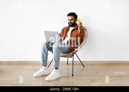 Eastern Guy Mit Laptop Und Bankkarte, Die Im Innenbereich Kaufen Stockfoto