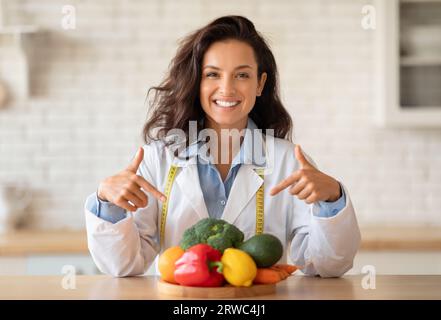 Porträt einer glücklichen kaukasischen Ernährungsberaterin, die frisches Obst und Gemüse trinkt, vor der Kamera lächelt, Kopierraum Stockfoto