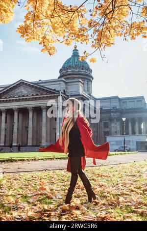 Mädchen in rotem Mantel mit Pelzmütze, die im Schnee posiert Stockfoto