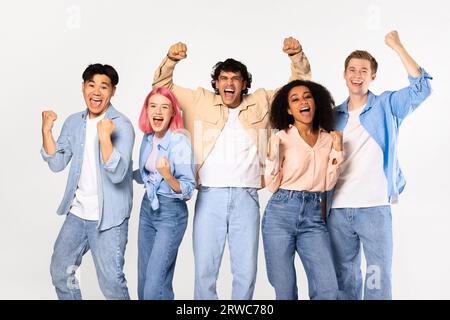 Fröhliche Teenie-Freunde, die schrien und Fäuste schütteln, sich vor der Kamera posieren und auf weißem Hintergrund stehen Stockfoto