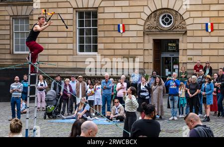 Straßenkünstler, der mit Feuerfackeln jongliert, während er auf einer Leiter steht, Edinburgh Festival Fringe, Parliament Square, Schottland, Großbritannien Stockfoto