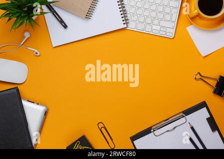 Gelber Hintergrund Chaos auf Desktop-Tastatur Maus Tasse Kaffee Business Computer Blume blaknot Stift Stockfoto