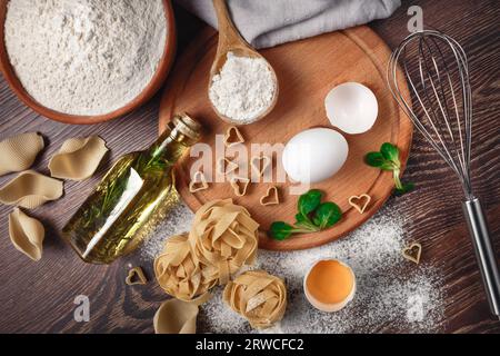 Zutaten für Bäckereien. Mehl mit rohen Eiern Ölsalat für Teignudeln auf Holzuntergrund Stockfoto