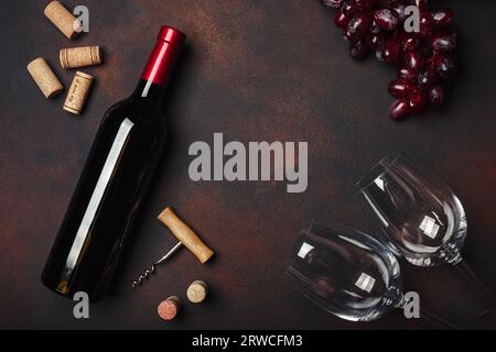 Flasche Wein, zwei Gläser, rote Trauben, Korkenzieher und Korken, auf rostigem Hintergrund Draufsicht, Kopierraum Stockfoto