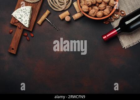 Flasche Wein, Blauschimmelkäse, Walnuss, Mandeln, Korkenzieher, Seil und Korken, auf rostigem Hintergrund, Draufsicht Stockfoto