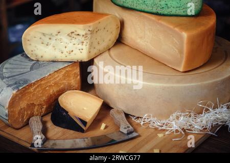 Nahaufnahme von Käseköpfen, gehackten Köpfen, Stücken von , Messer mit , Käse in den Regalen Stockfoto