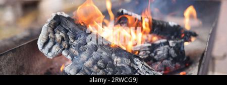 Brennholz in einer langen Metallgrillnaht. Stockfoto