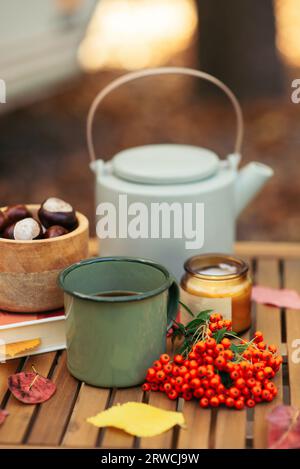 Eine Tasse Tee oder Kaffee und ein Buch auf einem Holztisch vor dem Hintergrund von gefallenen Blättern, Herbstsaison, Stillleben mit Blättern, ein Buch und Viburnu Stockfoto
