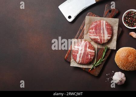 Hamburger Zutaten roh Schnitzel, Salat, Brötchen und Zwiebel auf Rusty Hintergrund. Ansicht von oben mit Platz für Ihren Text. Stockfoto