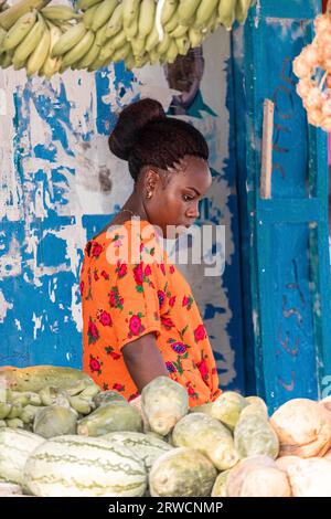Schönes afrikanisches Mädchen auf dem Hintergrund von Gemüse auf dem Markt. Natürliche Produkte. Stockfoto