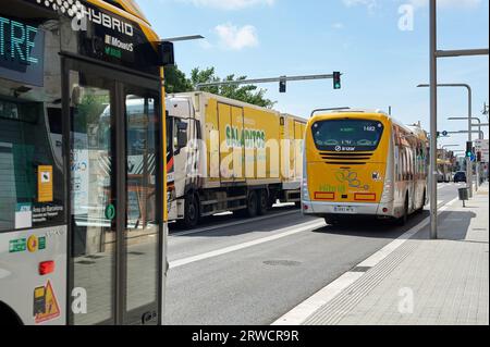 Viladecans, Spanien - 18. September 2023: Stadtbusse teilen sich die Straße mit knickgelenkten Lastkraftwagen Stockfoto