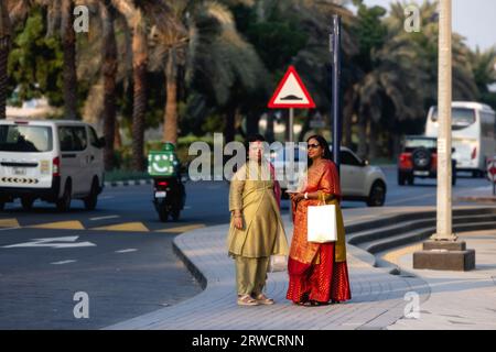 Dubai, VAE - Januar 20221: Zwei indische Frauen mit bunten Saris warten auf ein Taxi in Dubai Stockfoto