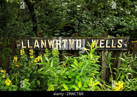 Llanwrtyd Wells, Powys, Wales, UK - altes Bahnhofsschild, umgeben von Pflanzen auf dem Bahnsteig im Herzen der Wales Line Stockfoto