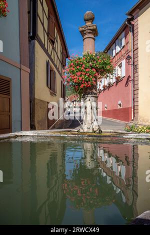 Hunawihr, Frankreich - 09 04 2023: Blick auf einen typischen Steinbrunnen mit bunten Blumen Stockfoto