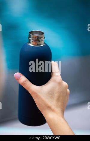 Nahaufnahme einer Hand, die eine wiederverwendbare Thermowasserflasche aus Stahl hält Stockfoto