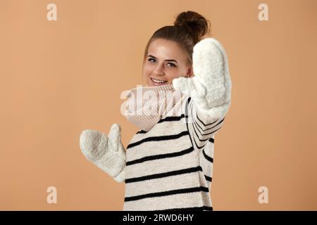Glückliche junge Frau in Wollpullover und Fäustlingen Stockfoto