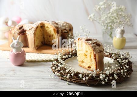 Köstlicher italienischer Oster-Taubenkuchen (traditionell Colomba di Pasqua) im Nest und festlicher Einrichtung auf weißem Holztisch, Platz für Text Stockfoto