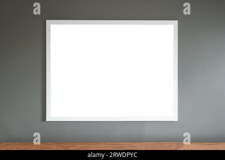 Weißes Rahmenbrett, das an der grauen Wandvorlage hängt, leeres mittiges Holzelement darunter Stockfoto