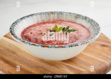 Gazpacho-Suppe mit Kräutern in einem tiefen Teller auf einem Holzbrett Stockfoto