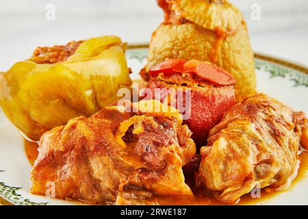 Gefüllte Zucchini, Paprika und Kohlrollen auf Teller mit einem Ornament auf Holzständer Stockfoto