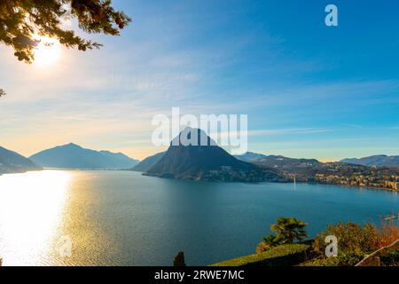 Baumzweig und Luganer See und Stadt mit Berg und blauem Himmel im Park San Michele in Castagnola in Lugano, Tessin in der Schweiz Stockfoto