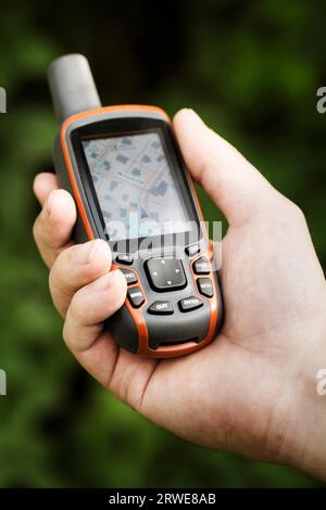 Mann, der einen GPS-Empfänger in der Hand hält. Handheld-GPS-Geräte werden vorwiegend in der Outdoor-Freizeitindustrie zum Wandern und Wandern eingesetzt Stockfoto