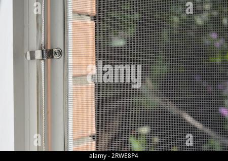 Moskitonetz. Nahaufnahme des Moskitogitters mit Metallhaltern am Fenster zum Schutz vor Insekten. Stockfoto