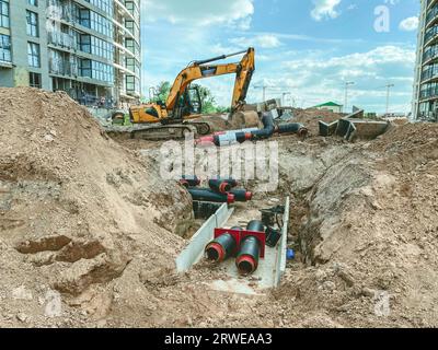 Bau eines neuen Stadtgebietes. Baugrube, Kabelverlegung und unterirdische Kommunikation. Große Rundrohre im Sand vergraben. Stockfoto