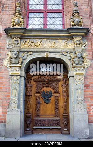 Reich dekorierte antike Tür auf einem historischen Apartmenthaus mit Meeresmotiven, Wappen und Wappen von Polen und Danzig in der Altstadt von Danzig Stockfoto