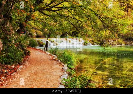 Herbstlandschaft mit Pfad entlang des Sees mit Wasserfall im Nationalpark Plitvicer Seen, Kroatien Stockfoto