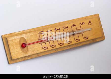 Raumthermometer auf einem Holzsockel, Nahaufnahme auf weißem Hintergrund. Grad Celsius. Stockfoto