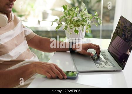 Abgeschnittenes Bild von Softwareentwicklern, die im Home-Office an Laptops arbeiten Stockfoto