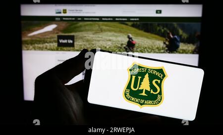 Person, die ein Smartphone mit dem Logo des United States Forest Service (USFS) auf dem Bildschirm vor der Website hält. Konzentrieren Sie sich auf das Display des Telefons. Stockfoto