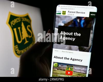 Person, die ein Mobiltelefon mit der Website des United States Forest Service (USFS) auf dem Bildschirm vor dem Logo hält. Konzentrieren Sie sich auf die Mitte der Telefonanzeige. Stockfoto