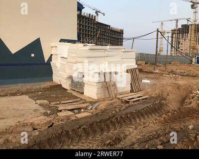 Schmutz auf einer Baustelle. Sandfurchen, Ketten von schweren Fahrzeugen. In der Nähe befinden sich Baumaterialien, Betonstücke und Holzpaletten. CON Stockfoto