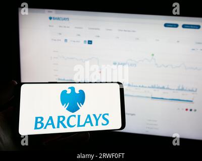 Person, die ein Mobiltelefon mit dem Logo der britischen Universalbank Barclays plc auf dem Bildschirm vor der Firmenwebseite hält. Konzentrieren Sie sich auf das Display des Telefons. Stockfoto