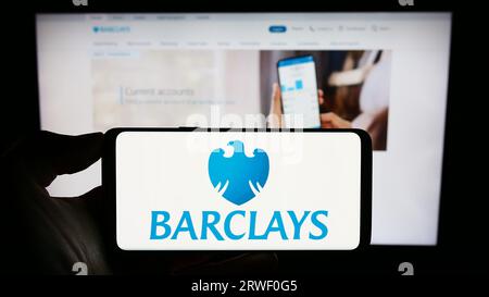 Person, die ein Mobiltelefon mit dem Logo der britischen Universalbank Barclays plc auf dem Bildschirm vor der Geschäftswebseite hält. Konzentrieren Sie sich auf das Display des Telefons. Stockfoto