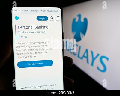 Person, die ein Smartphone mit einer Webseite der britischen Universalbank Barclays plc auf dem Bildschirm vor dem Logo hält. Konzentrieren Sie sich auf die Mitte der Telefonanzeige. Stockfoto