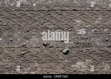 Nahaufnahmen von Reifen verfolgen Lkw auf einer unbefestigten Straße bei Tageslicht. Stockfoto