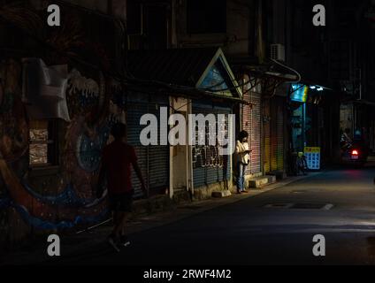 Taiwanesische Frau, die ihr Handy nachts auf einer Straße ansieht, Taipeh, Taipeh, Taiwan Stockfoto